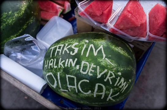 Revolutionary melon slices for a revolutionary market. The slogan scratched onto the watermelon: "Taksim, the people's revolution is coming." But, no matter how progressive, red, and tasty such melon slices may have been, the going price -- five lira per serving -- was counter-revolutionary at best! (Fuji X100) (Click on image to enlarge).