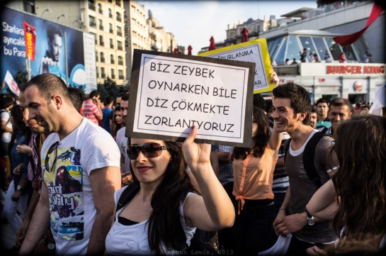 The Turkish Prime Minister announced that he would never kneel before "looters/freebooters" occupying Gezi Park and the marchers demonstrating on their behalf.  This marching folklorist carries a sign liberally translated as: "Even when we dance Zeybek (a traditional dance involving crouching steps), we do not kneel!"