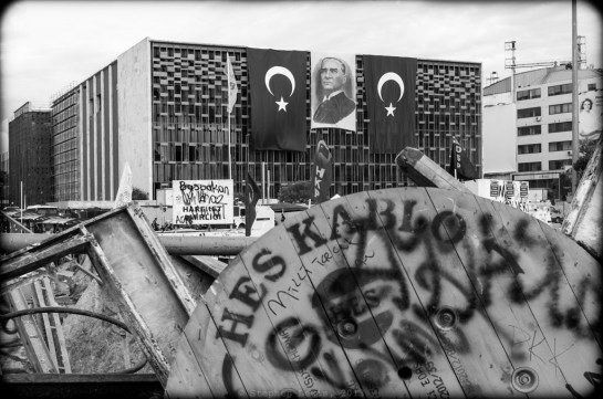 Atatürk Curlutral Center, the morning after a brutal siege by police a week and a half ago.  Immediately after the siege, the police removed banners hung by left-wing groups and replaced them with a portrait of Atatürk flanked by two Turkish flags.  In an uncharacteristic departure from the usual iconography of of the present regime, a portrait of Prime Minister Erdoğan is conspicuous in its absence. (Fuji X100).  (To magnify image, click on photo)
